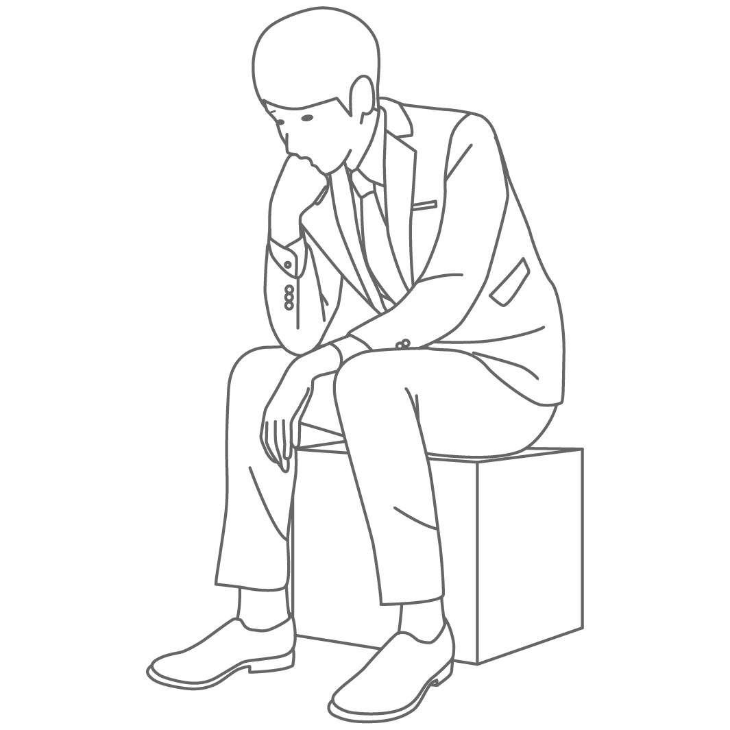 スーツを着た男性が箱に座りながら下を向いて何かを考えている