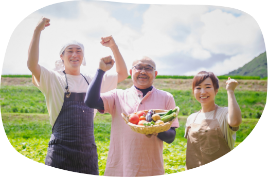 かごに入った野菜を持った男性を中心に若い夫婦が両脇に立ち笑顔でこぶしを上げている